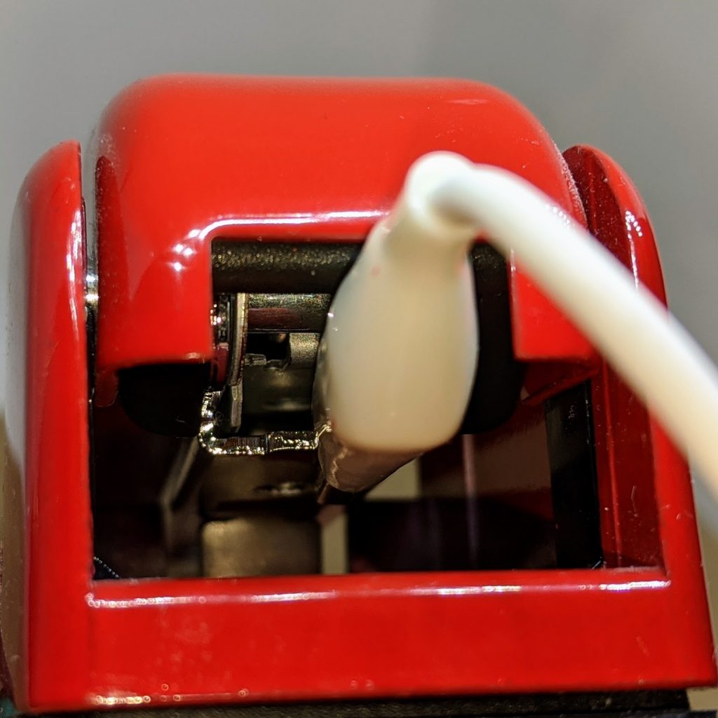 rear of stapler with white alligator clip protruding, clipped to staple dispenser