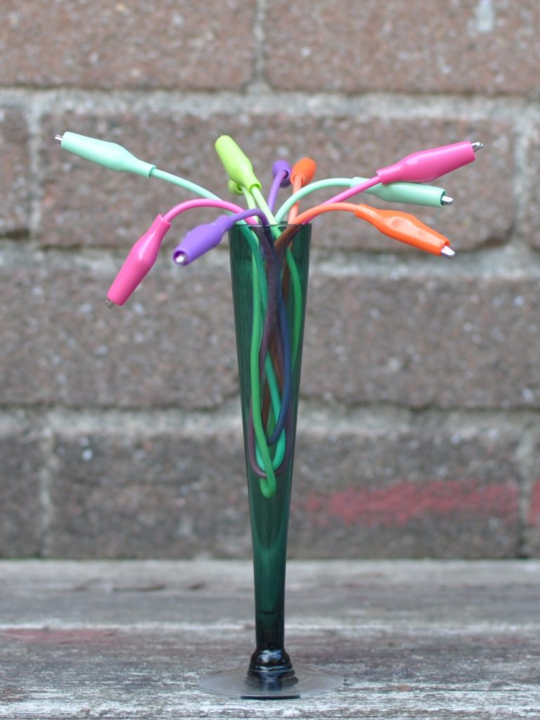 multi-colour alligator clips arranged in a green bud vase as if they were flowering buds