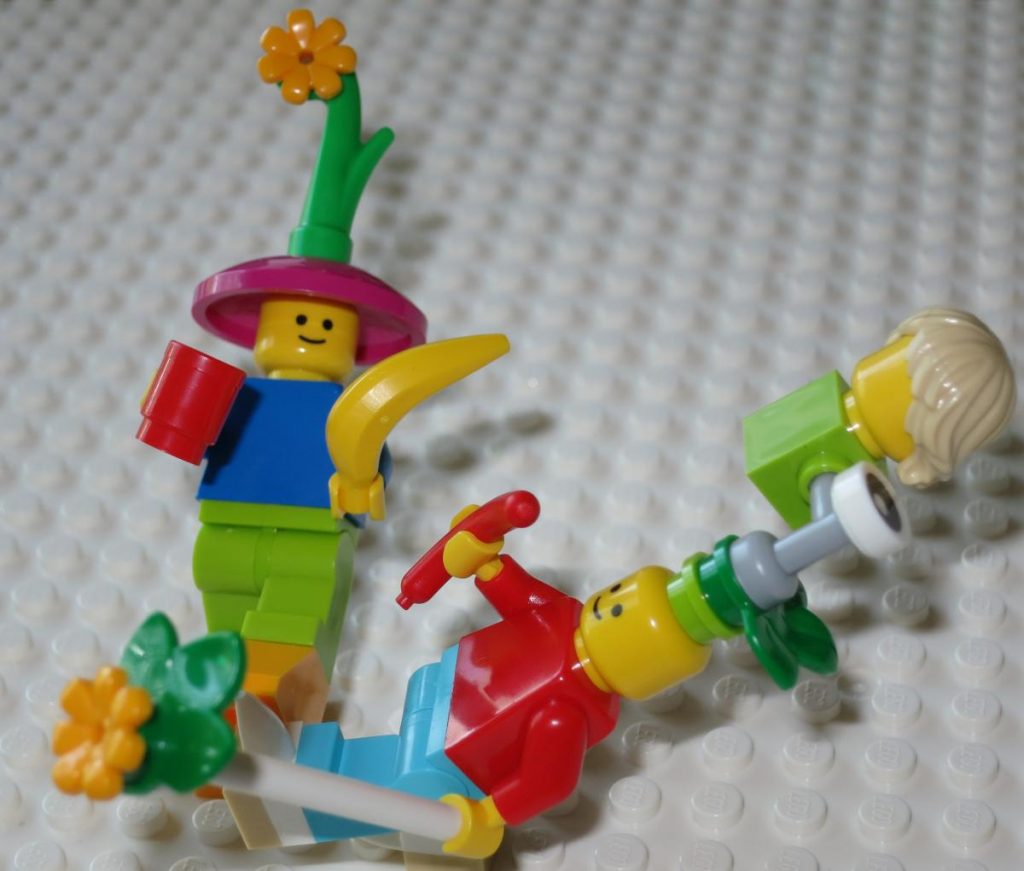 two Lego minifigs with lots of bizarre accoutrements half-facing each other and leaning back on one foot