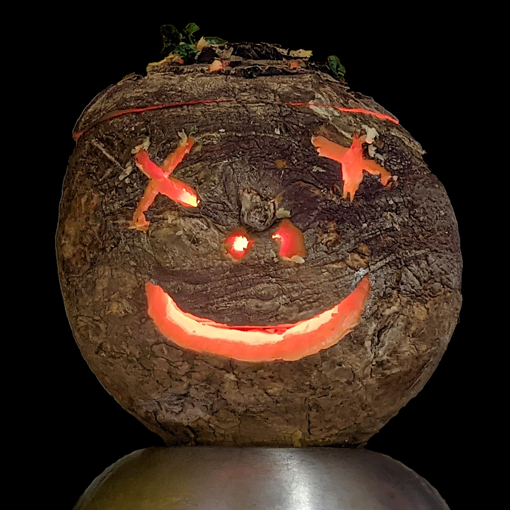 carved swede/turnip with eyes cut out as crosses, two nostrils and a lopsided grin lit from inside by a small candle.

(the smell is fairly atrocious, but emotive of the day)