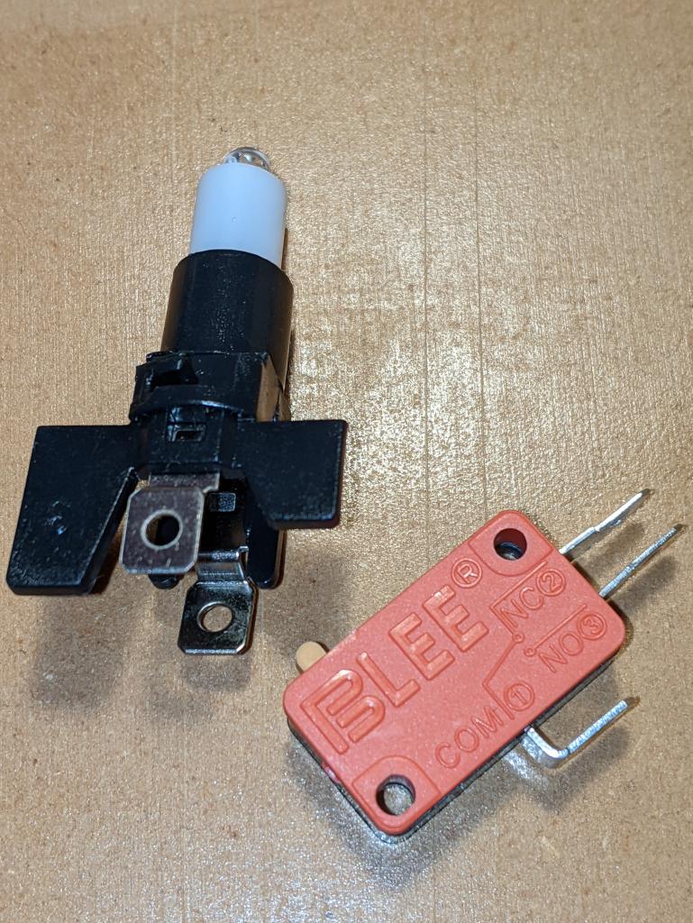 the LED holder at left, and the bare microswitch. The LED holder has an LED in a white plastic retainer, and below it two spade contacts. The switch has three spade connectors: Com(mon) on the base, and "NO 3" (Normally Open) and "NC 2" on the right side. Normal operation connects COM and NO