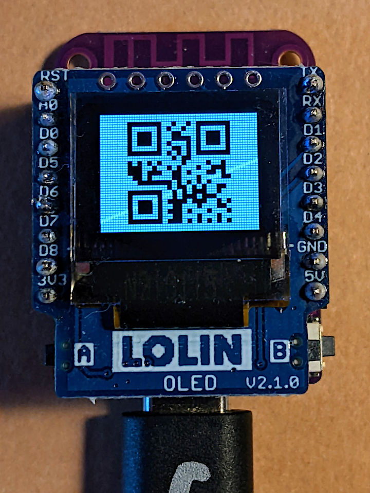 small microcontroller board with USB C cable attached and an OLED screen on top. The OLED is displaying a QR code which reads '172731'