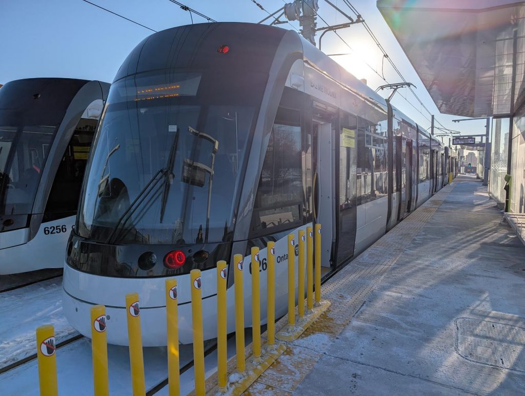 Two Alstom TTC/Metrolinx Crosstown light rail trains sit at the rather snowy Aga Khan Park station
